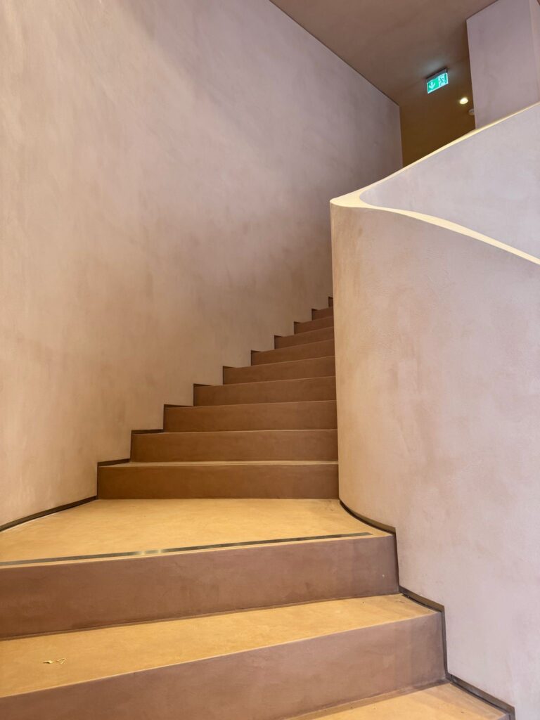 ClayLime - Natural clay concrete staircase at CAIA Cosmetics flagship store in Stockholm, applied by Creative Coatings with ClayLime's Wonderstone."